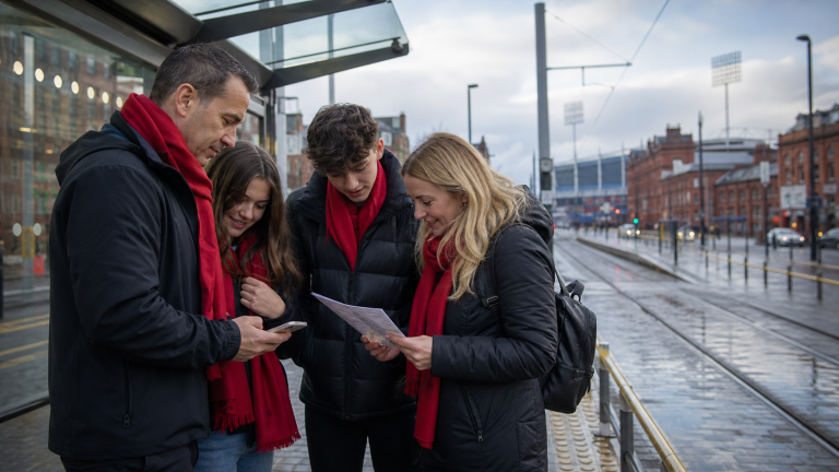 Familj planerar resvägen till en fotbollsmatch vid en spårvagnshållplats i Manchester